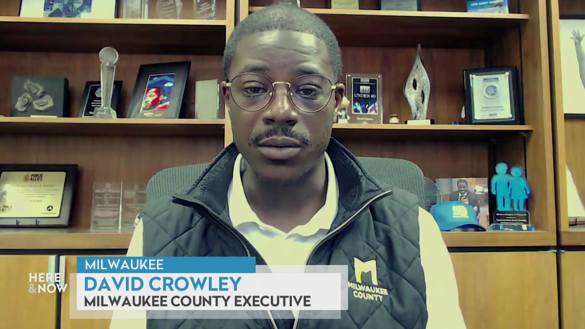 A still image shows David Crowley seated in front of a shelf containing many awards and photos with a graphic at the bottom that reads 'Milwaukee,' 'David Crowley' and 'Milwaukee County Executive.'